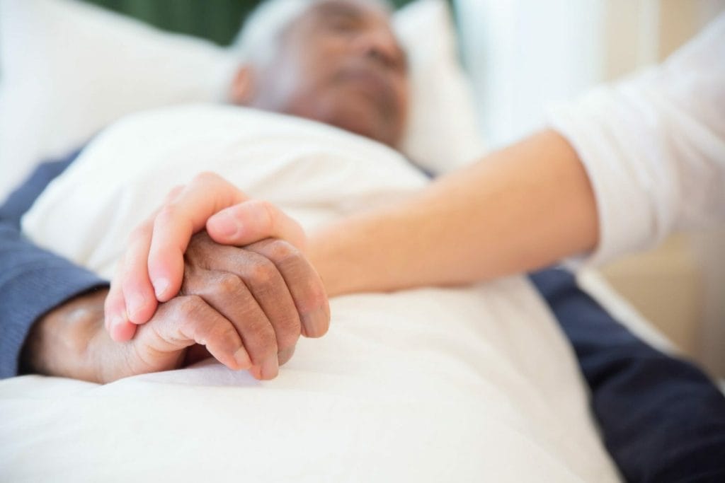 hospice care giver holding hand